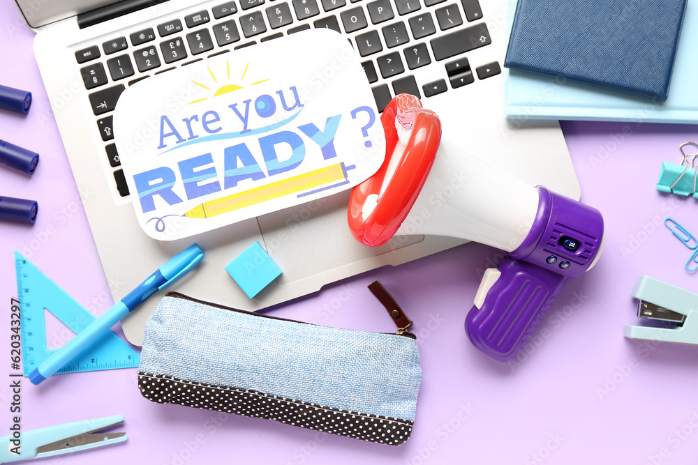 Stationery, laptop, megaphone and sheet with question ARE YOU READY? on lilac background