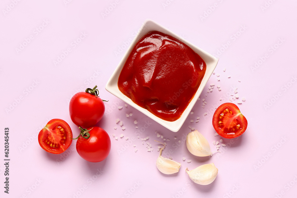 Bowl with tomato paste and fresh vegetables on lilac background