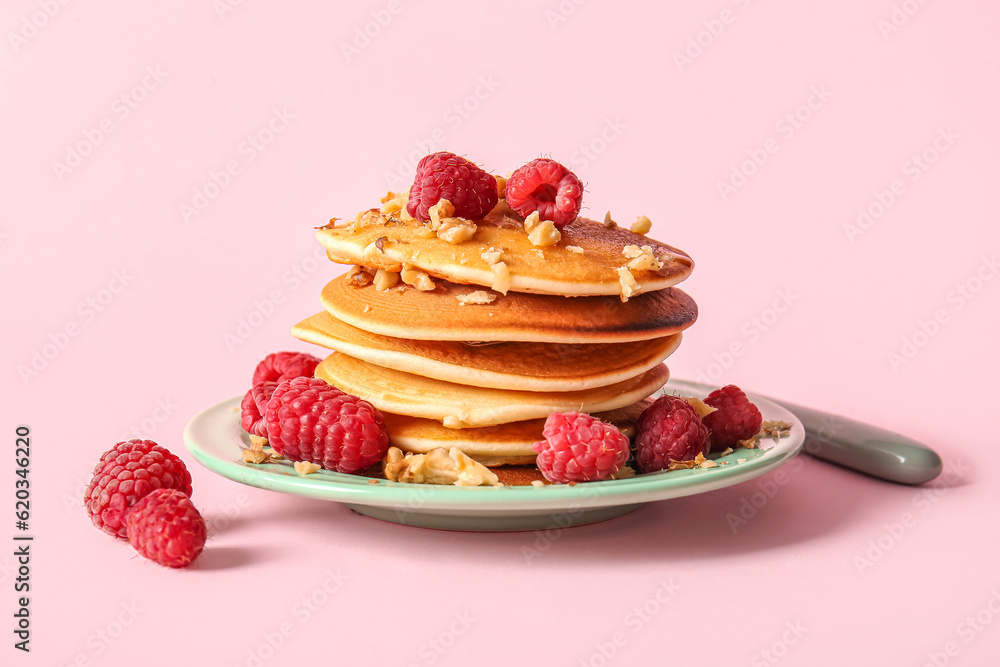 Plate of tasty pancakes with raspberries on pink background