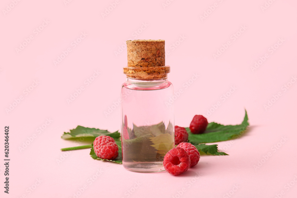 Bottle of cosmetic raspberry oil on pink background