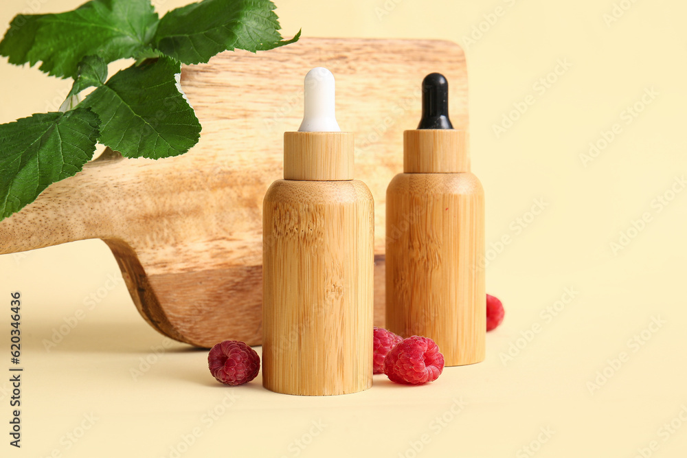 Bottles of cosmetic raspberry oil on yellow background