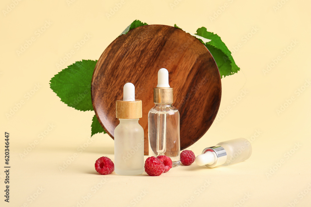 Bottles of cosmetic raspberry oil on yellow background