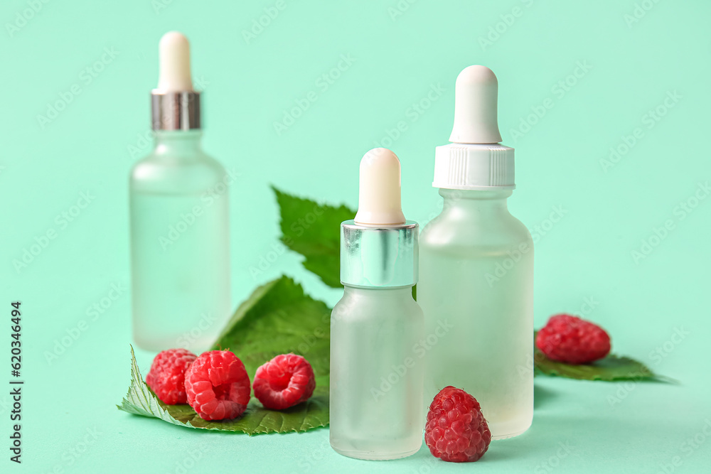 Bottles of cosmetic raspberry oil on blue background