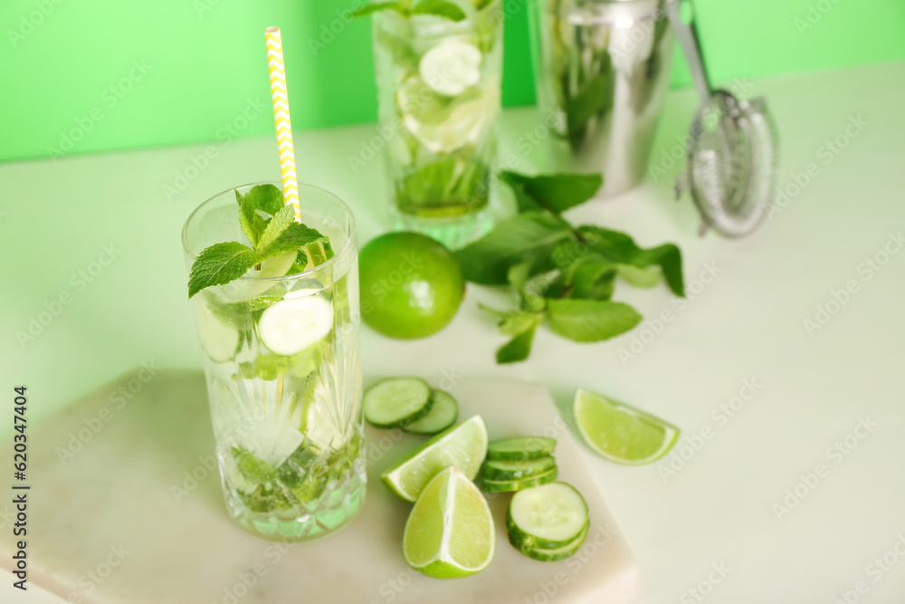 Glasses of mojito cocktails with cucumber, lime and mint on green background