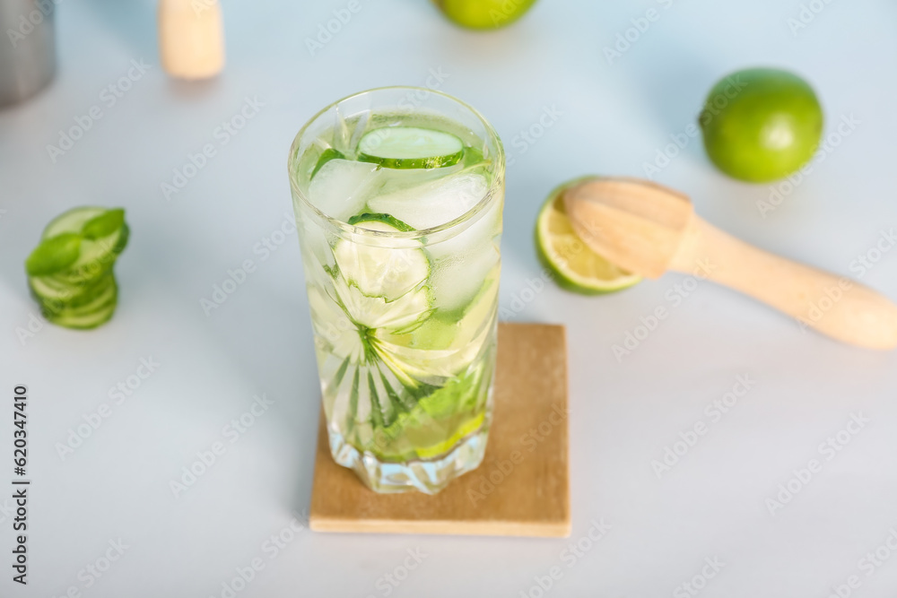 Glass of fresh cucumber mojito on light background