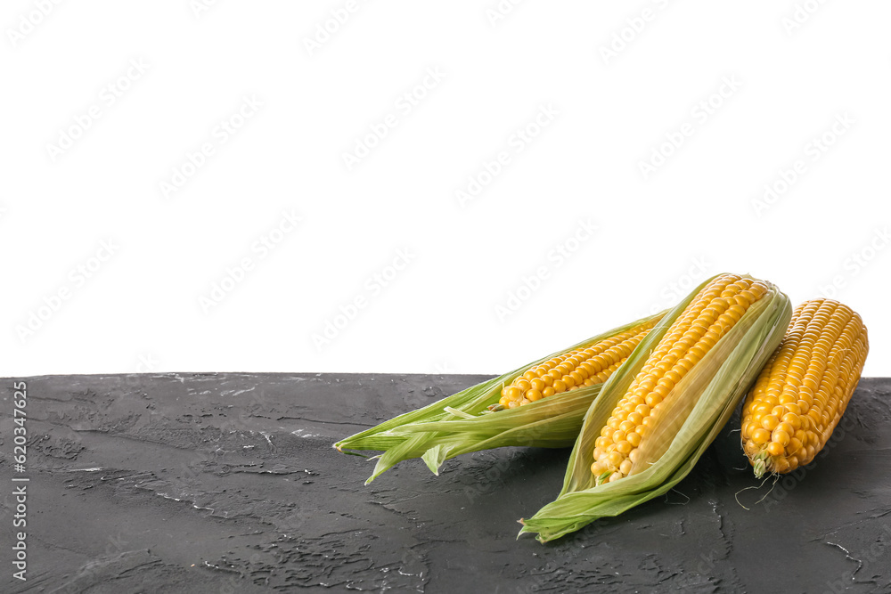 Fresh corn cobs on black table against white background