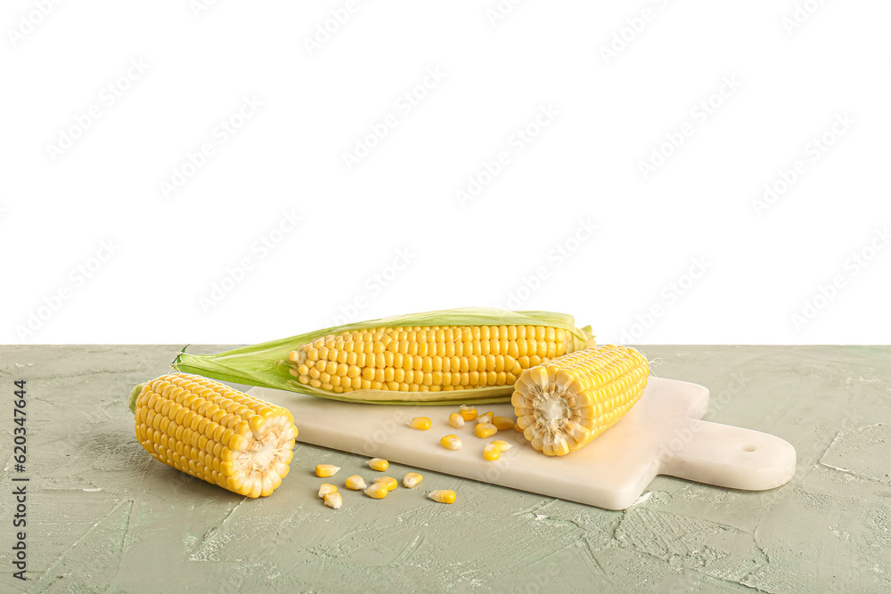 Board with fresh corn cobs and seeds on grey table against white background