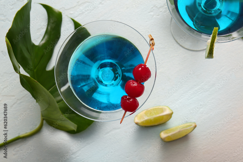 Glasses of tasty cocktail with maraschino cherries on light background