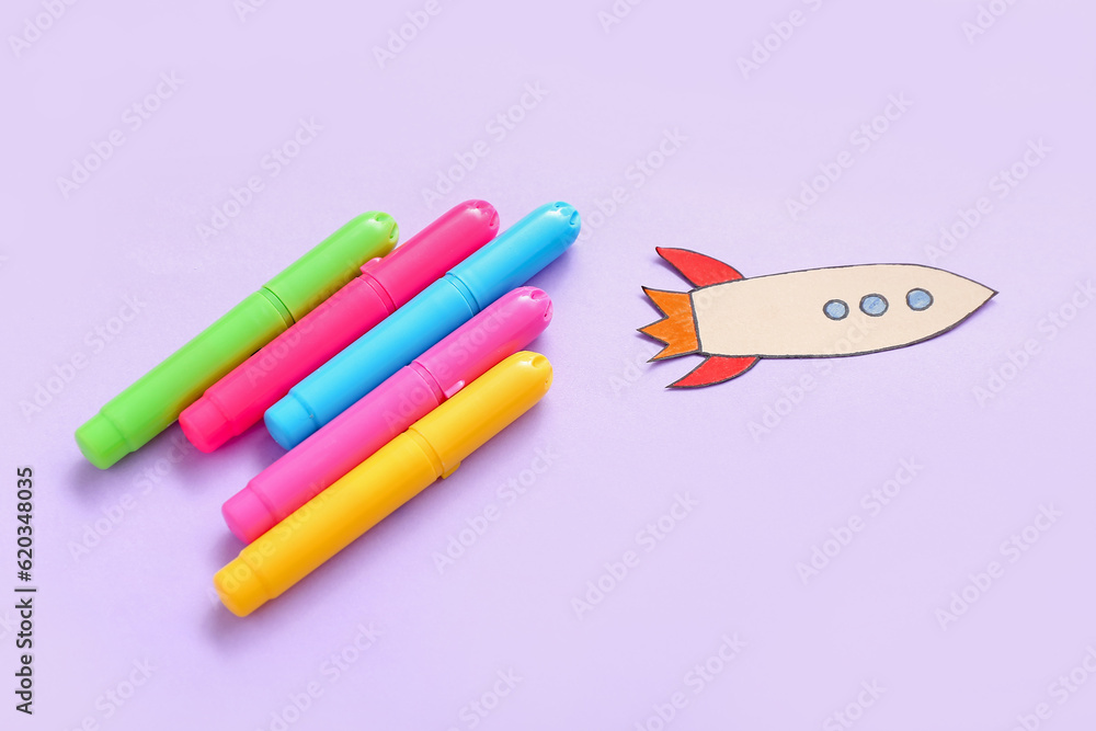 Markers with paper rocket on purple background