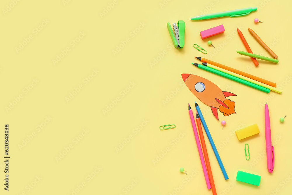 Paper rocket with school stationery on yellow background