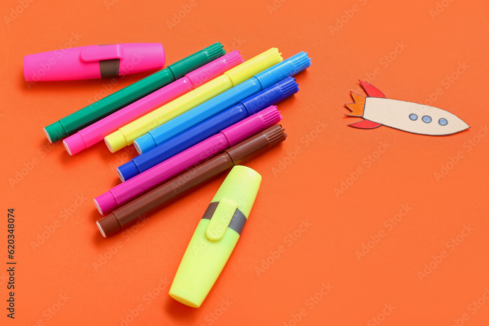 Markers with paper rocket on red background