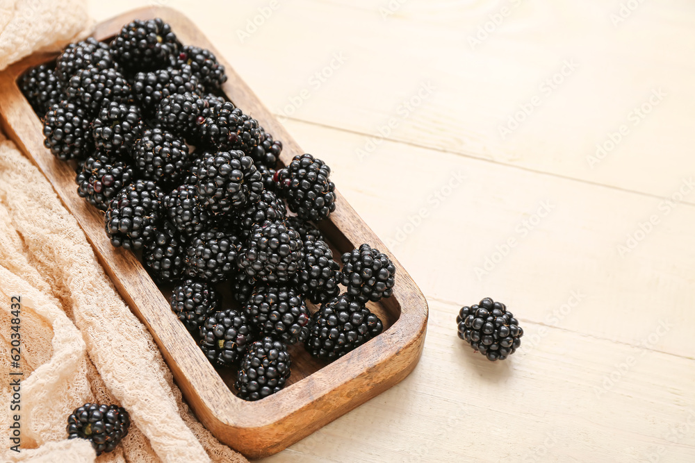 Board with fresh blackberry on light wooden background, closeup