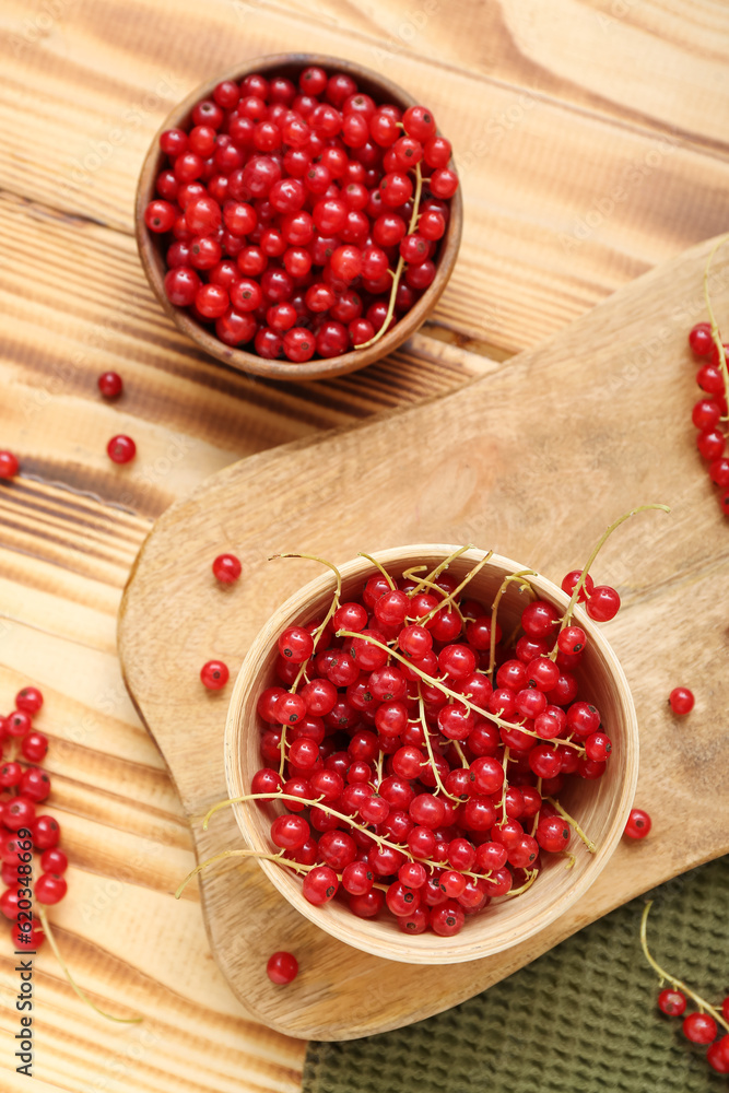 Bowls with fresh red currant on wooden background