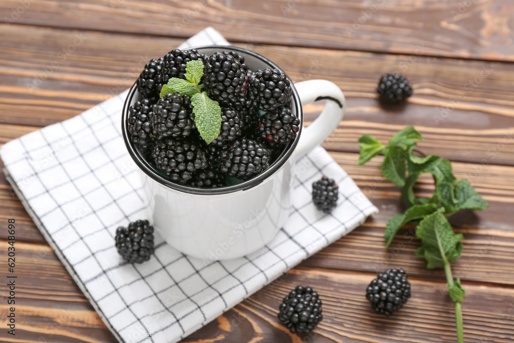 Cup with fresh blackberry and mint on wooden background, closeup