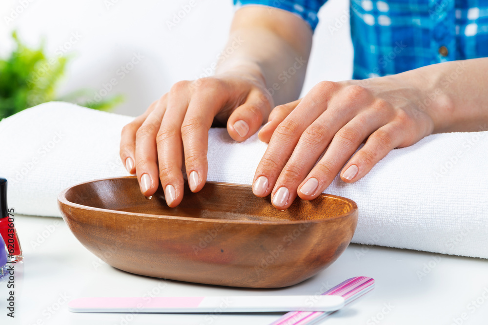 Closeup female hands in wooden bowl with water