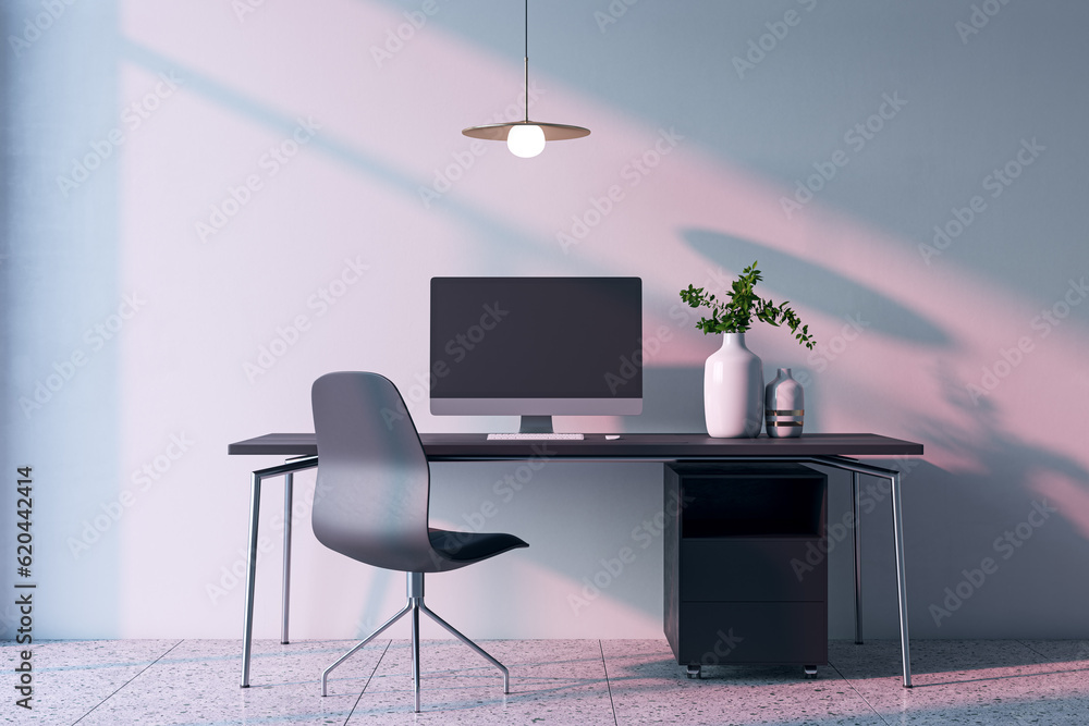 Modern home office interior with computer, furniture and other items. Concrete wall with shadows in 