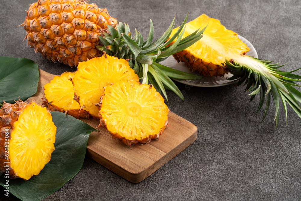 Fresh cut sliced pineapple in a plate over dark gray table background.