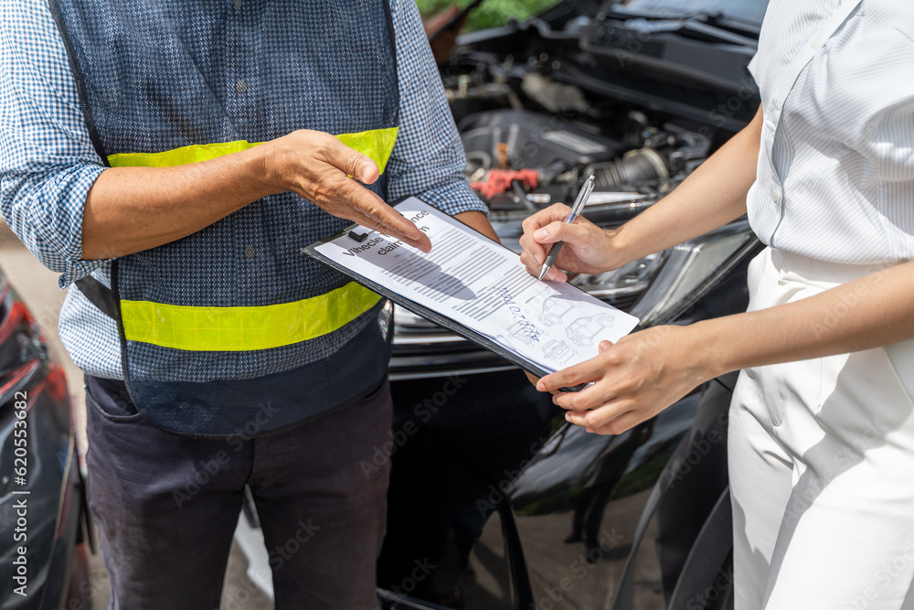 Close up of a car insurance agent showing the woman customer where to sign the car insurance claim f