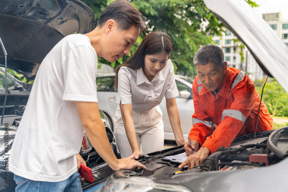 Car machanic showing the man and woman the problem of their cars engine while parking on the side o