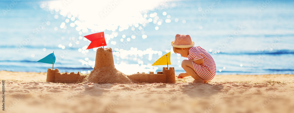 Little boy building sand castle on the sea beach.