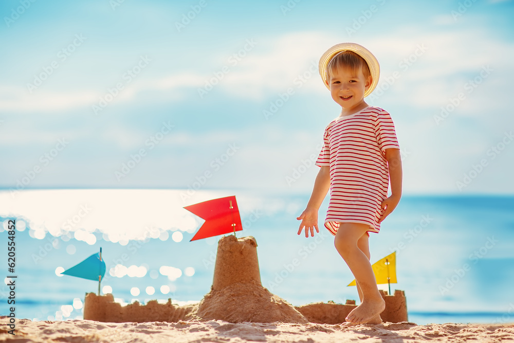 Little boy building sand castle on the sea beach.