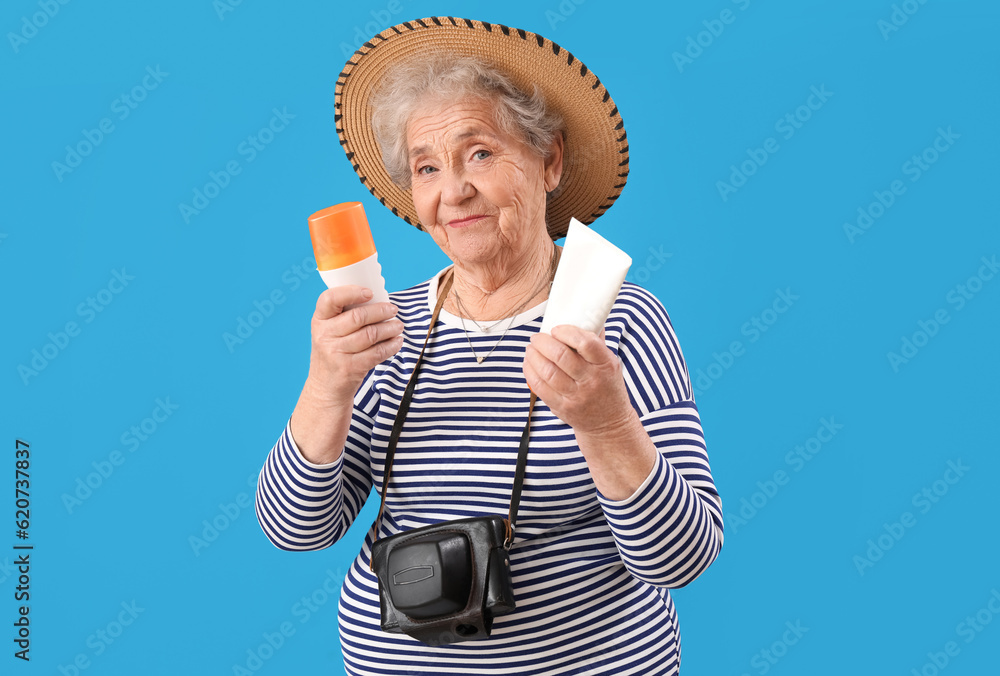 Senior woman with sunscreen cream on blue background