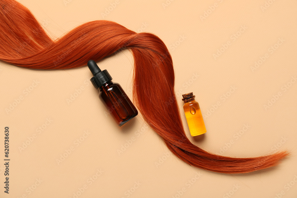 Ginger hair strand and bottles of essential oil on color background, closeup