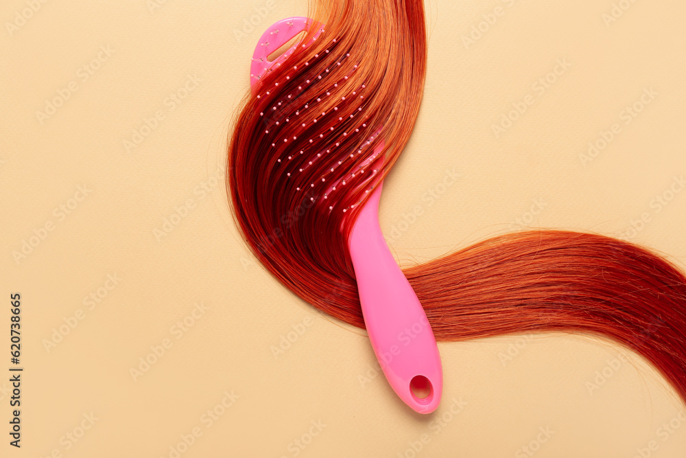 Ginger hair strand and brush on color background, closeup