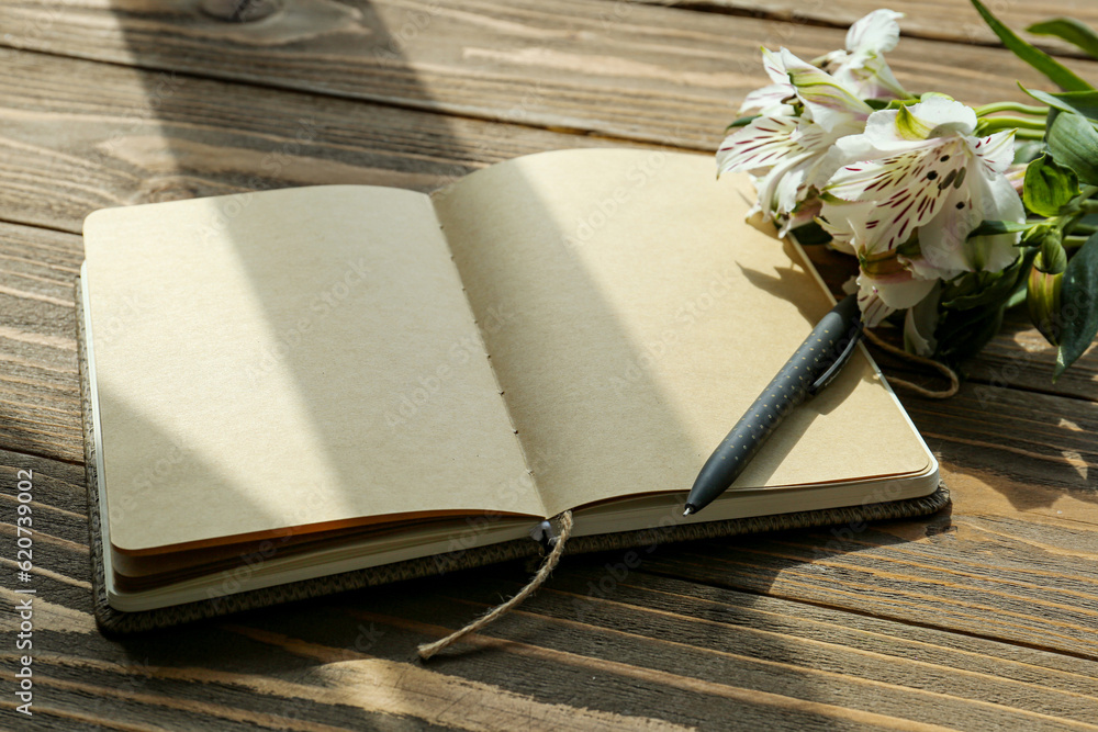 Blank open notebook, pen and beautiful alstroemeria flowers on wooden background