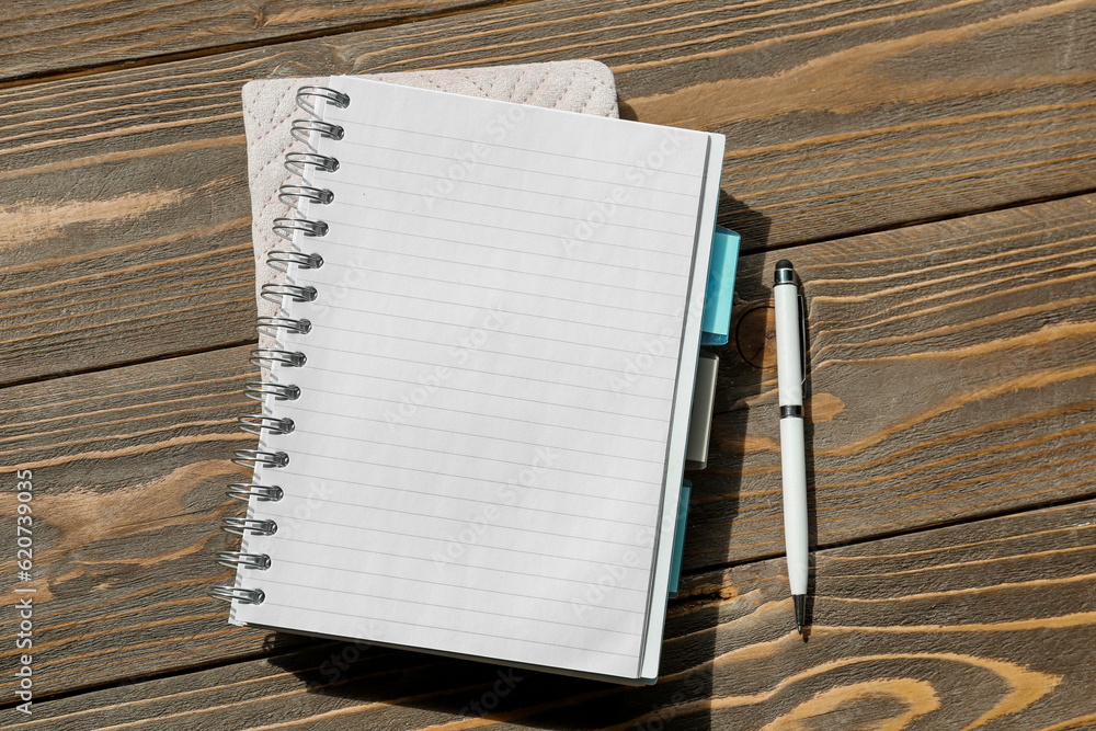 Blank notebook with pen on wooden background