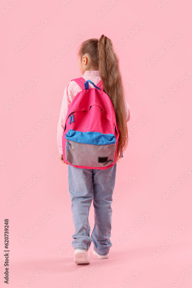 Little schoolgirl with backpack on pink background, back view