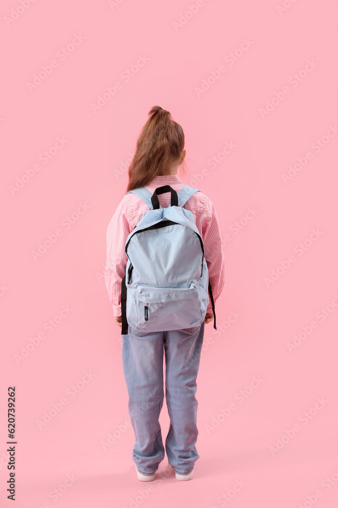 Little schoolgirl with backpack on pink background, back view