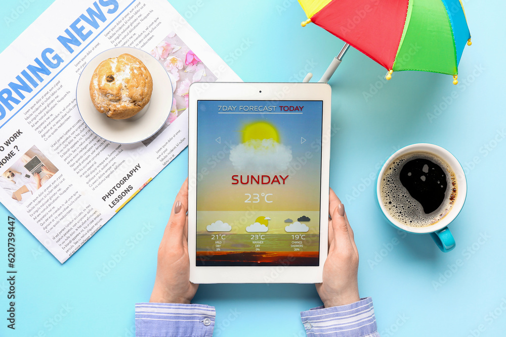 Woman holding tablet computer with weather forecast on blue background