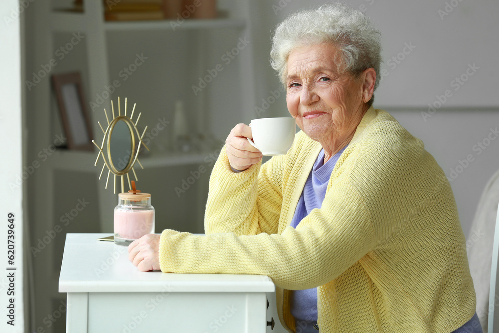 Senior woman with cup of coffee sitting at home