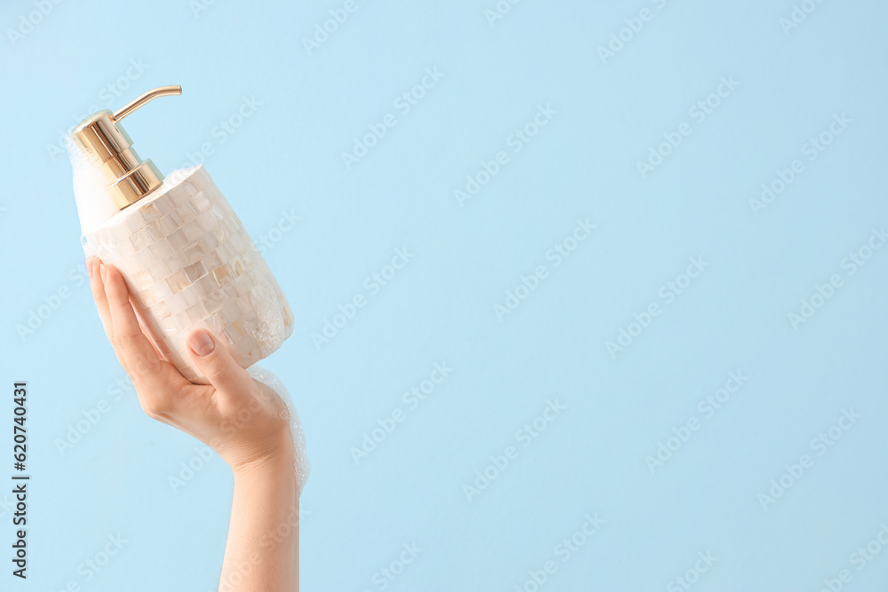 Hand with liquid soap on light blue background