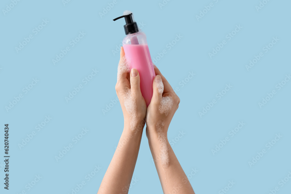 Hands with liquid soap on light blue background