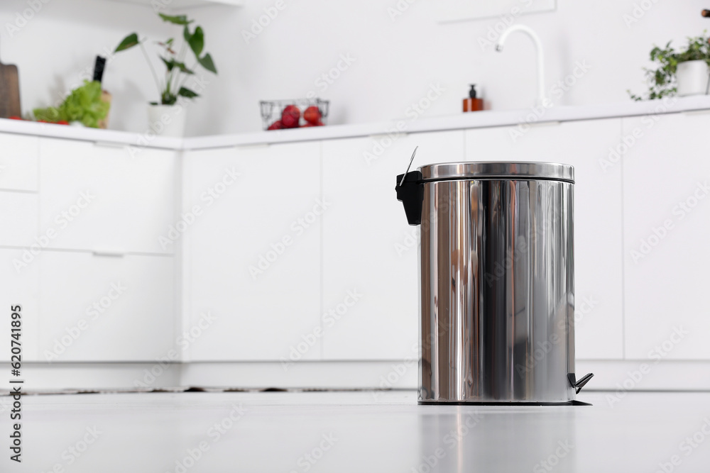 Metallic trash bin in interior of light kitchen