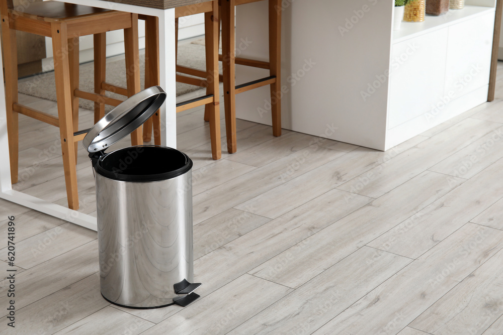 Opened trash bin in interior of light kitchen