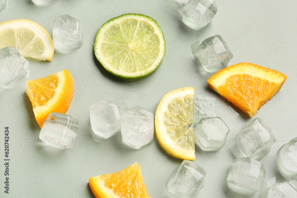 Citrus slices with ice cubes on green background