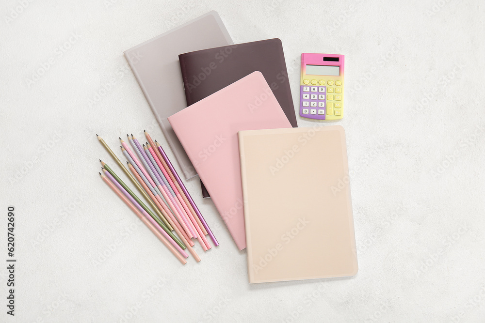 Different colorful notebooks with pencils and calculator on white background