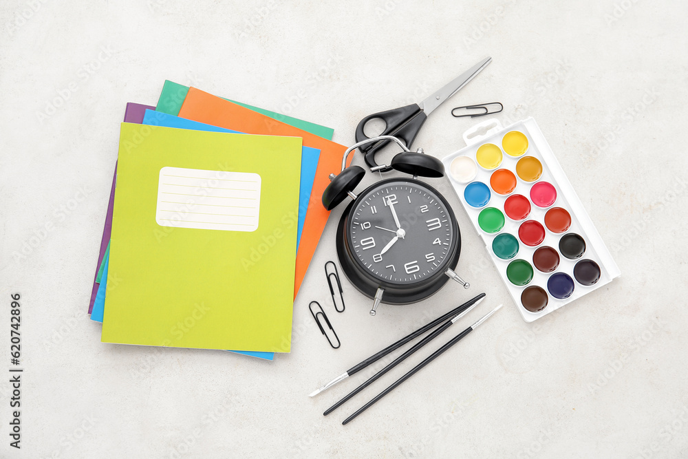 Alarm clock with different stationery on beige background