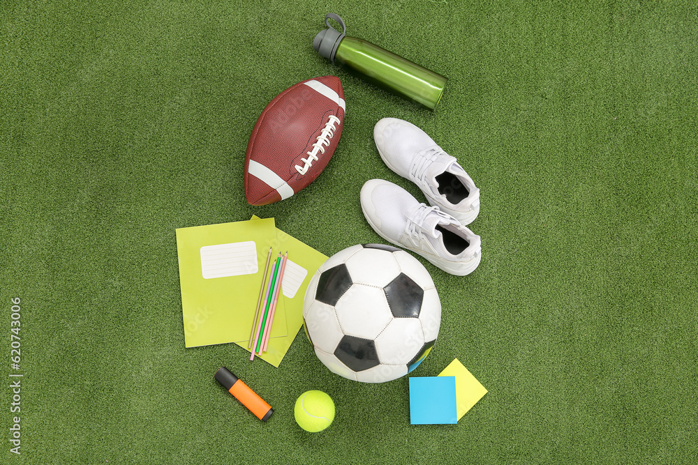 Sneakers with sport balls, bottle of water and different stationery on color background