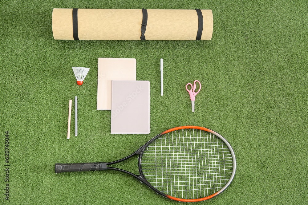 Yoga mat with racket, badminton shuttlecock and different stationery on color background