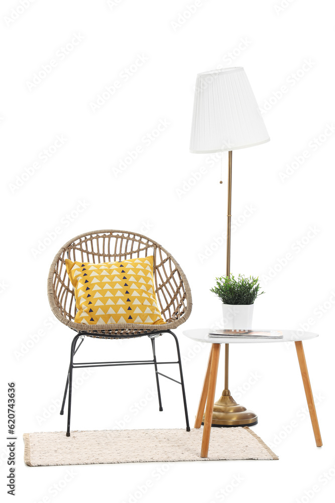 Cozy armchair with table, lamp and rug on white background