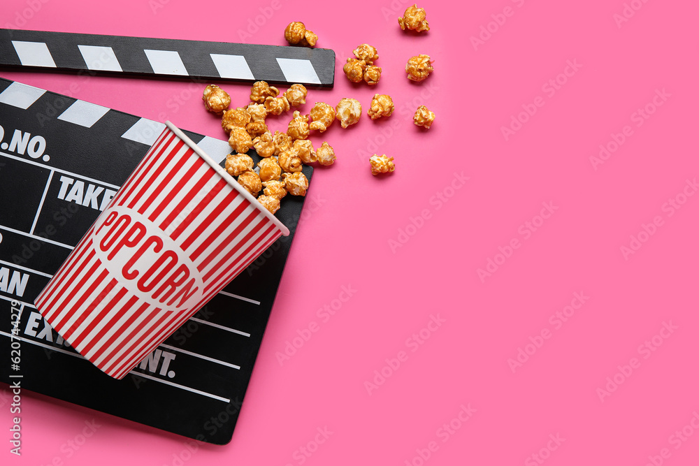 Bucket with tasty popcorn and clapperboard on pink background