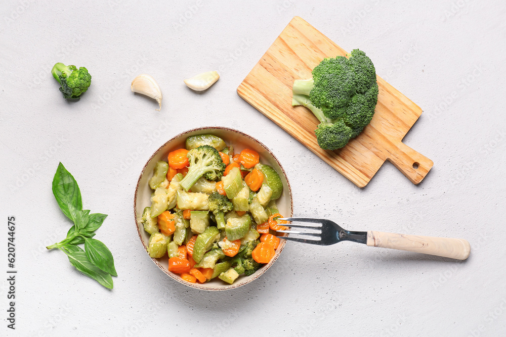 Bowl with different vegetables on light background