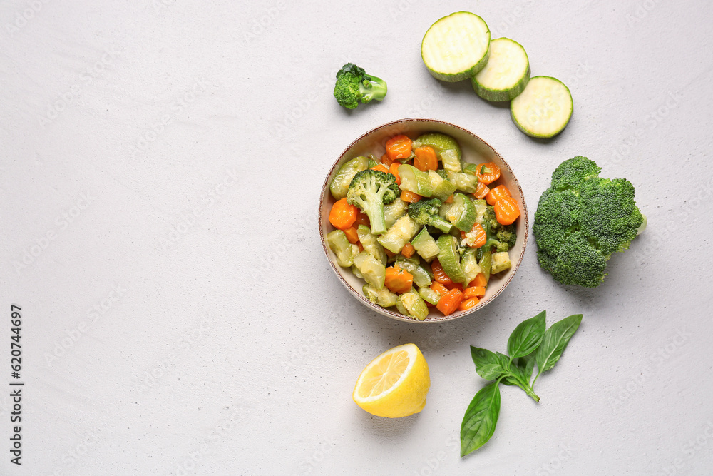 Bowl with different vegetables on light background