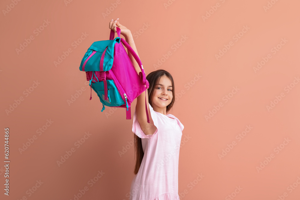 Little girl with backpack on pink background