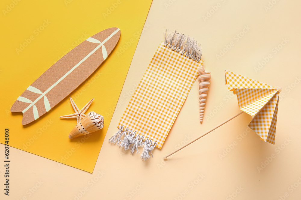 Creative summer composition with mini surfboard, umbrella and beach blanket on color background