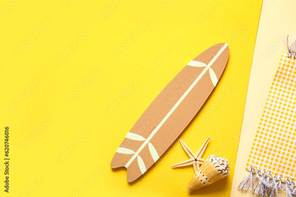 Creative summer composition with mini surfboard, umbrella and beach blanket on color background